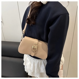 Detail of beige leather shoulder bag with oval gold buckle and adjustable strap