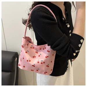 Close-up of the cherry print pattern and pink fabric texture on this shoulder bag