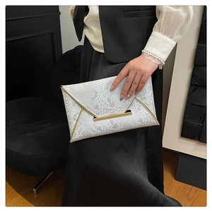Detail view of silver snakeskin clutch bag with metallic gold trim and envelope flap design