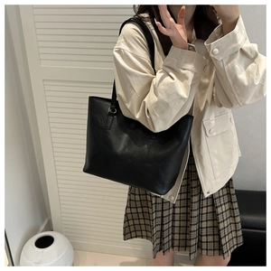 Borsa tote minimalista in pelle nera con tracolla mostrata in un contesto casual lifestyle