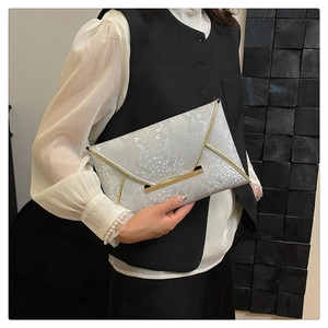 Close-up of silver snakeskin clutch bag with gold metal trim held by a model