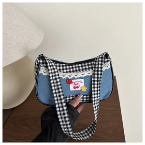 Detail of blue denim hobo bag with gingham trim, lace lace edge, and cherry patch