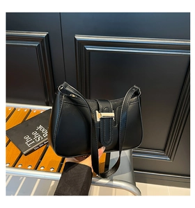 Détail d'un sac sous le bras noir en forme de croissant avec boucle dorée élégante