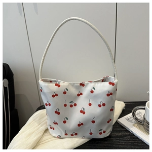 Detailed view of white fabric handbag with red cherry print on white textured cloth