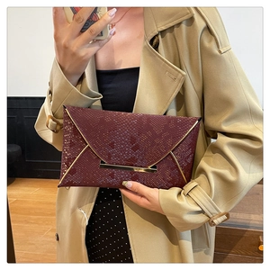 Detail showing the burgundy snakeskin-patterned envelope clutch with gold metal edge trim