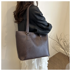 Borsa tote marrone scuro con trama a grana indossata da modella per prova di misura