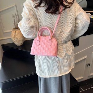 Pink quilted shell handbag with gold hardware and shoulder strap shown by a model