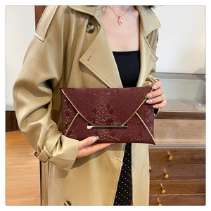 Detail view of burgundy snakeskin envelope clutch bag with elegant gold metal trim decoration