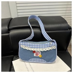 Detail of blue denim canvas bag featuring lace trim, cherry patch, and blue checkered strap