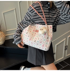 Detail of sweet print tote bag with bear motifs, woven pink handles, and plush charm