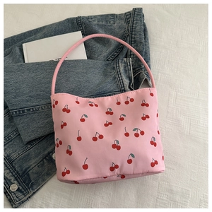 Detailed view of pink cherry print shoulder bag on white textured background
