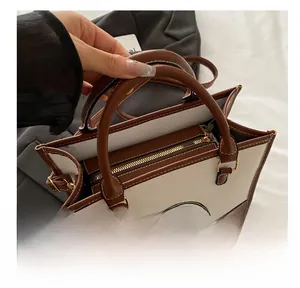 Close-up of vintage canvas tote bag showing top zipper closure and brown leather handles