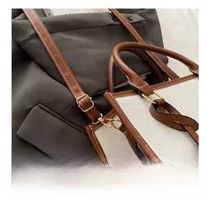 Detail of adjustable metal buckle on canvas tote bag with brown leather trim
