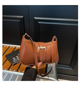Détail d'un sac sous le bras en cuir marron avec boucle métallique et fine bandoulière