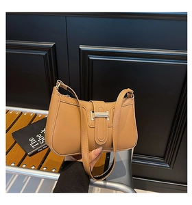 Vue détaillée du sac bandoulière en cuir caramel avec boucle vintage sur banc en bois