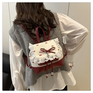 Close-up of ballet-style backpack with lace trim, red bow, and silver heart charm