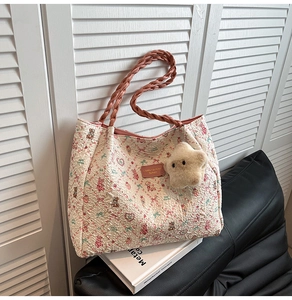 Close-up of seersucker tote bag with pink floral patterns and plush star charm