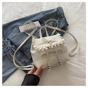 Detail of cream white mini backpack with ruffled flap, bow and pearl decoration
