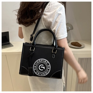 Detail of black structured tote bag with white contrast stitching and round logo