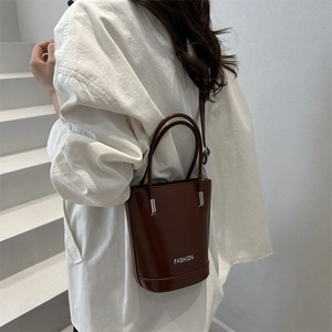 Classic dark brown leather bucket bag with top handles and adjustable shoulder strap