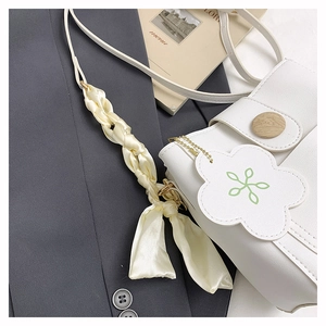 Detail der weißen Leder-Beuteltasche mit Holzmaserung-Schnalle und Seidenschal-Dekor