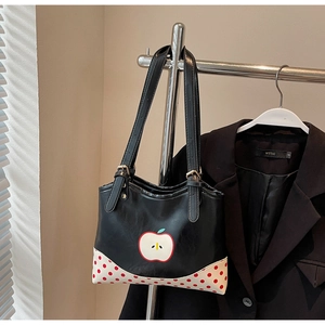 Detail of cute apple print and red polka dot pattern on black leather tote bag