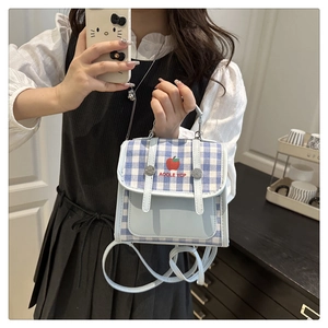 Detail of blue plaid canvas bag featuring red apple design and detachable shoulder strap