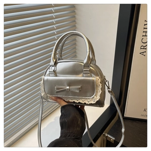 Detail of silver metallic handbag with bow decoration and white lace trim