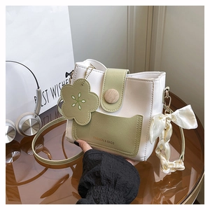 Detail of trendy color-block bucket bag with wood buckle, floral charm and silk scarf