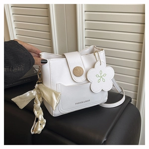 Detail of white bucket bag with floral charm and wood grain magnetic closure