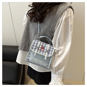 Detail of blue and white checkered crossbody bag with red apple motif and metal lock