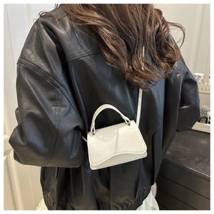 Close-up of white mini shoulder bag with crocodile texture and elegant wave flap design