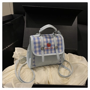 Detailed view of a light blue plaid crossbody bag presented in a black luxury gift box