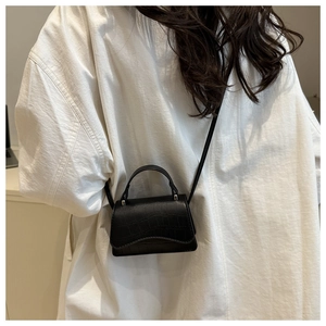 Détails de la texture crocodile noire et des finitions argentées sur un mini sac à bandoulière