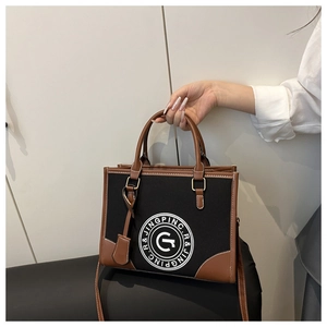 Detail shot of the two-tone canvas tote bag featuring brown leather trim and shoulder strap