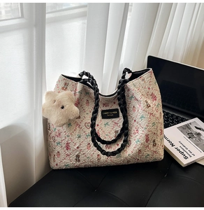 Detail of cream tote bag with bear print, textured wavy surface and plush star charm