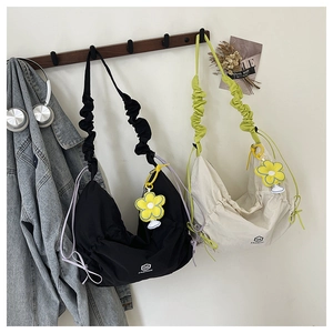 Detail of pleated dumpling bags in black and beige with ruffle straps and flower charms