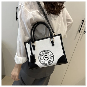 Detail view of large canvas tote bag with contrast leather trim and logo on model