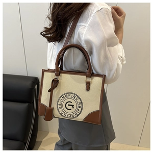 Close-up of beige canvas and brown leather stitching with logo on a vintage tote bag