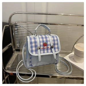 Detail of light blue plaid crossbody bag featuring apple pattern and silver metal clasp