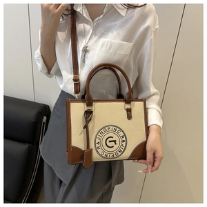 Detail of retro canvas tote bag showing beige fabric, brown leather trim and shoulder strap