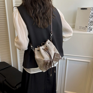 Beige canvas drawstring bucket bag with brown leather trim and detachable shoulder strap