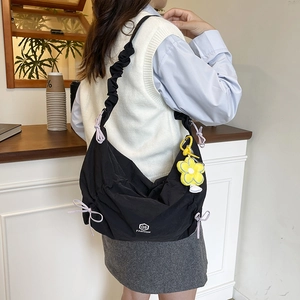 Minimalist black nylon dumpling shoulder bag with purple bows and yellow flower charm