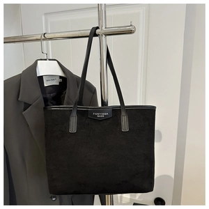 Detail of black suede tote bag with brand label and long shoulder straps for daily use
