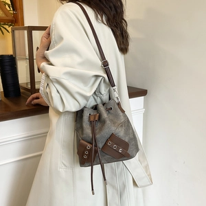 Retro grey canvas bucket bag with brown leather trim and drawstring in a side-view shot