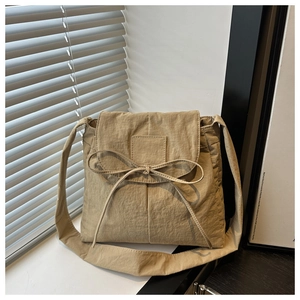 Detail of khaki nylon shoulder bag featuring a large bow tie and soft pleated texture