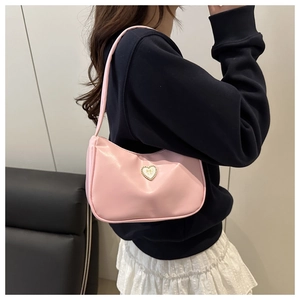 Close-up of pink leather shoulder bag featuring a gold heart-shaped buckle and bow detail