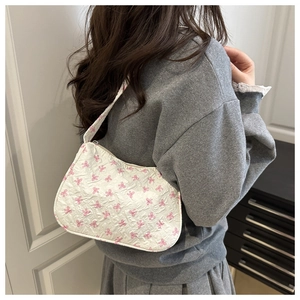Detailed back view of a white shoulder bag with pink bow patterns on a model's shoulder