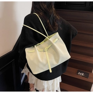 Detail of light green litchi texture tote bag with slim straps on wooden stairs