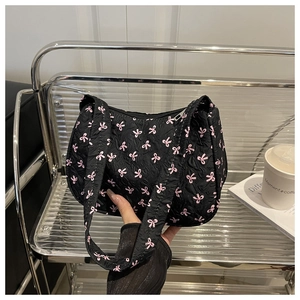Detail of black quilted shoulder bag with pink bows and bubble texture fabric